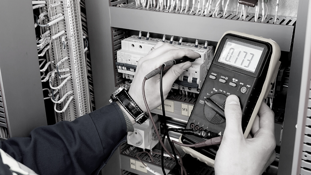 Elektriker misst Spannung im Schaltschrank mit Multimeter.